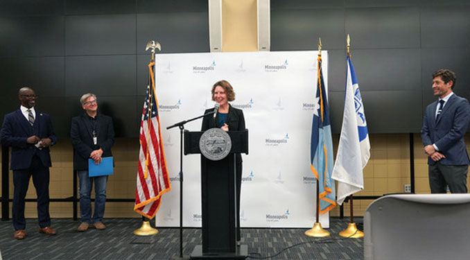 Director Rachel Sayre speaks at the podium at the swearing in ceremony held on Oct. 21 at the City’s Emergency Operations and Training Facility. From left to right, Office of Community Safety Commissioner Todd Barnette, City Clerk Casey Carl, Director Sayre, and Mayor Jacob Frey (SOURCE: Minneapolis Office of Community Safety)